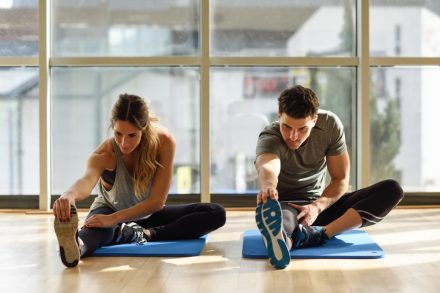 une femme et un homme faisant des étirements sur tapis de gym