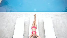 femme étendue en maillot de bain sur un transat au bord d'une piscine