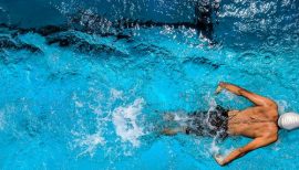 homme de dos nageant en piscine