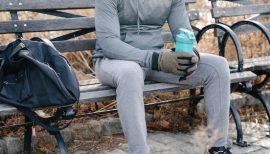 homme assis sur un banc, sac de sport posé sur l'assise.