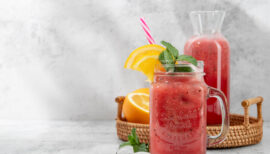 smoothie dans un grand verre agrémenté d'une feuille de menthe, paille et tranche d'orange