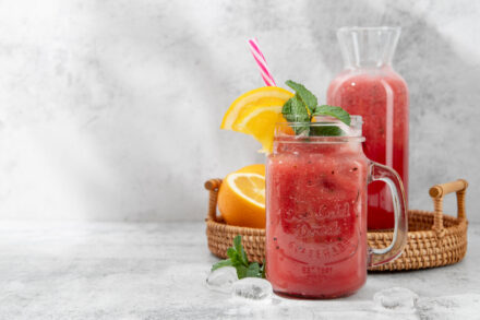 smoothie dans un grand verre agrémenté d'une feuille de menthe, paille et tranche d'orange