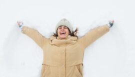 femme allongée sur la neige avec un grand sourire