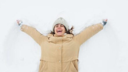 femme allongée sur la neige avec un grand sourire