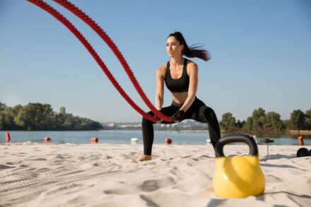 femme sportive utilisant une corde de cross-training sur la plage pour s'entraîner