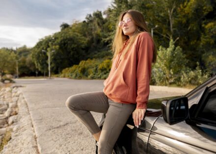 femme assise sur l'avant de sa voiture en voyage