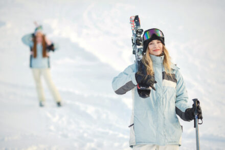 femme souriante à la montagne, skis sur l'épaule