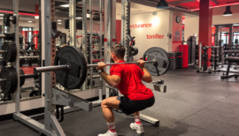 homme faisant un squat en salle de sport
