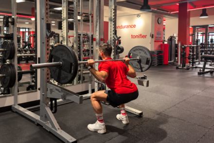 homme faisant un squat en salle de sport